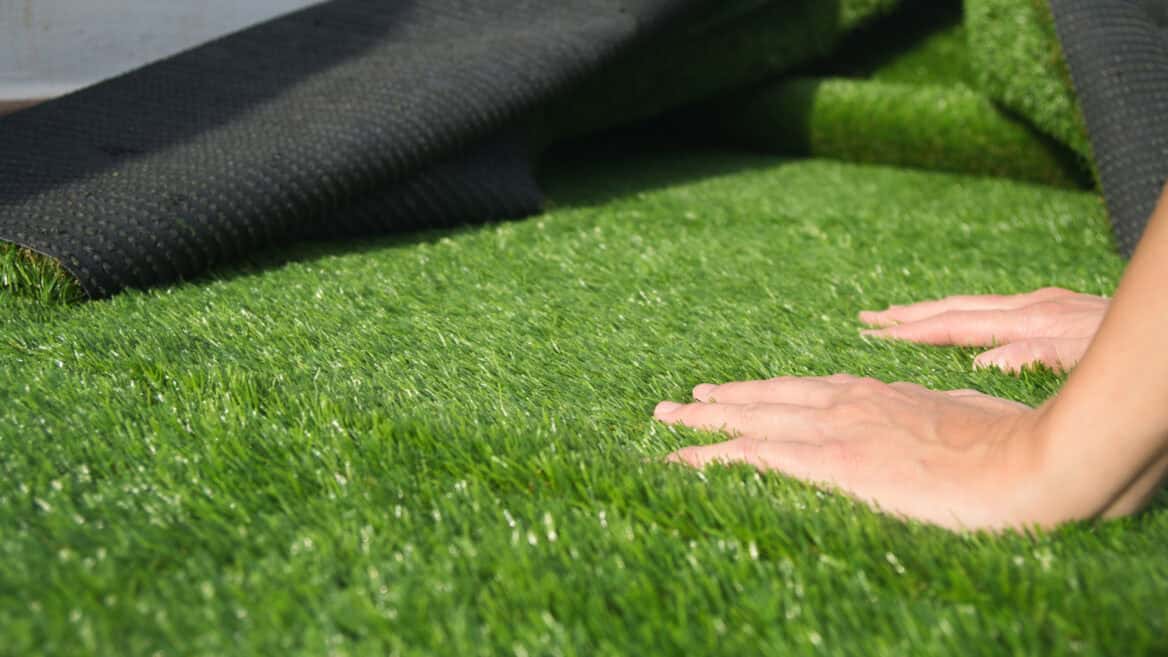 close up of a mans hands during installation of artificial grass