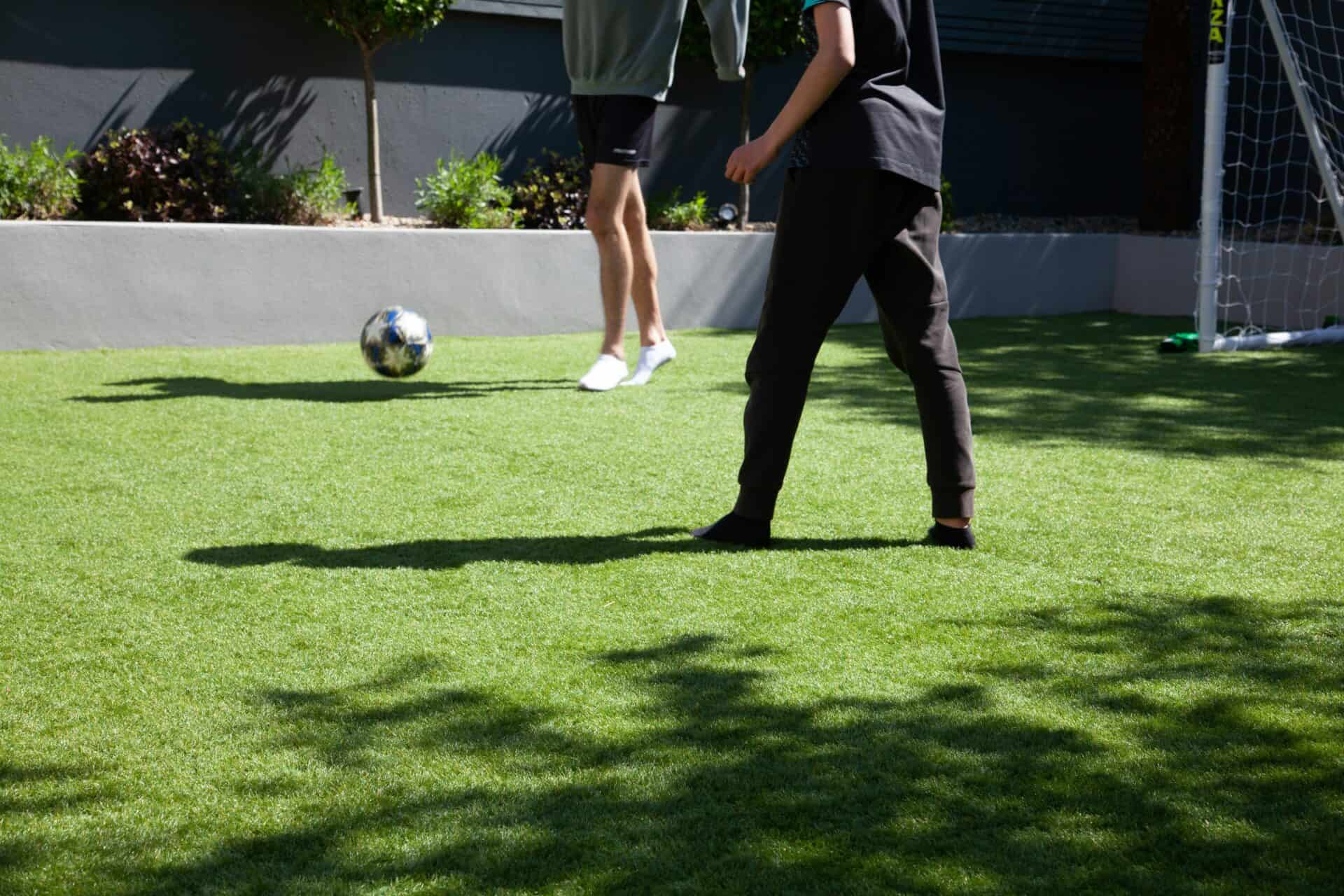 two people playing soccer in their backyard with artificial grass